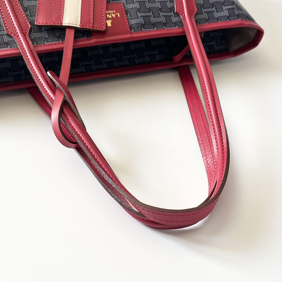 Close view of the navy weave, red handle and hanging tag