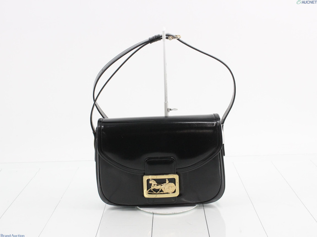 Front view of the black patent flap bag with gold carriage clasp