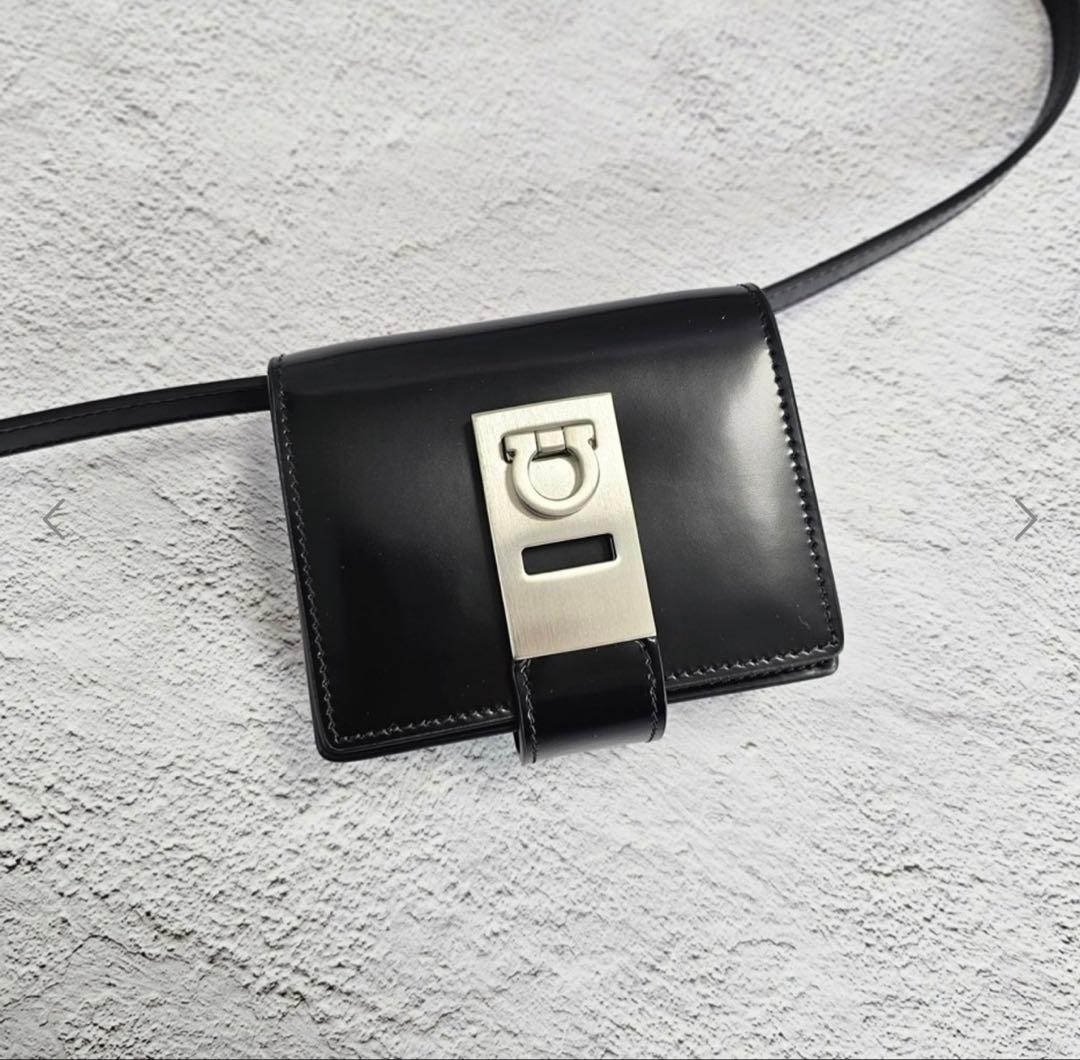 Flat-lay of the Gancini wallet-on-strap with the strap coiled