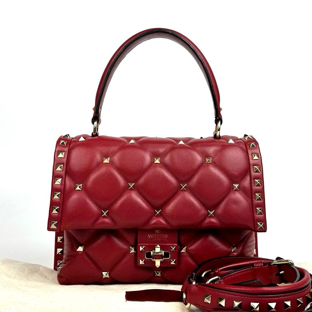 Red quilted top-handle bag with gold pyramid studs and detachable strap