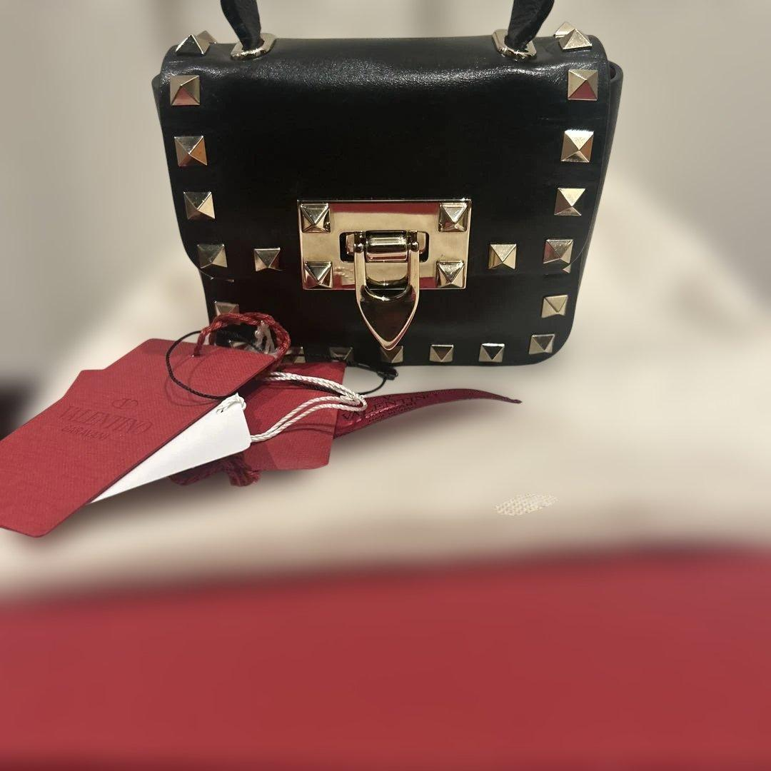 Black studded mini top-handle bag shown with original tags