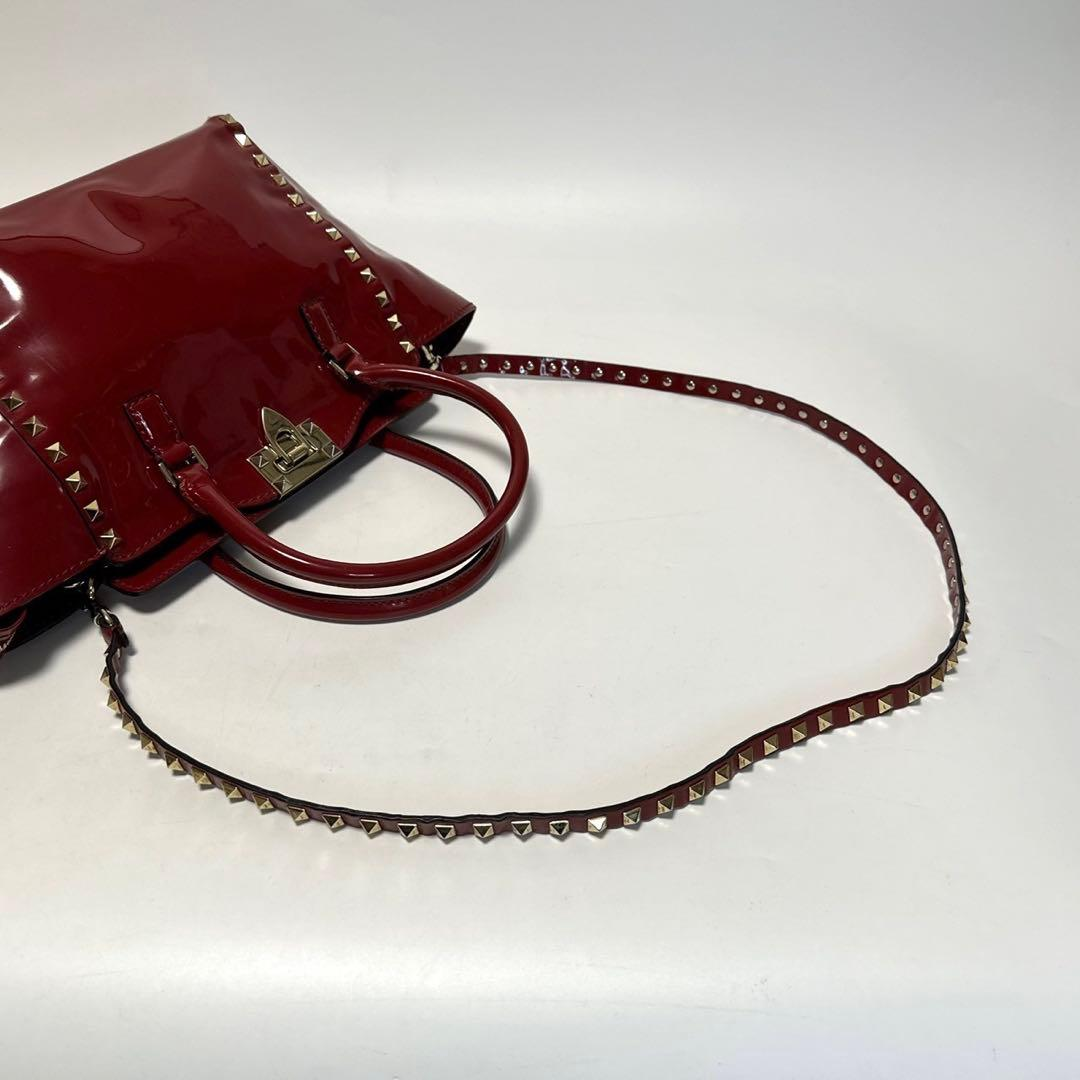Oxblood patent tote with its long studded shoulder strap