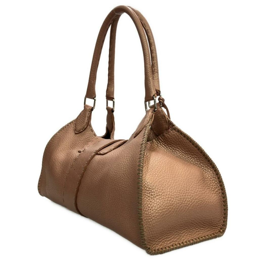 Angled view showing the whipstitched side seam of the tan dome bag
