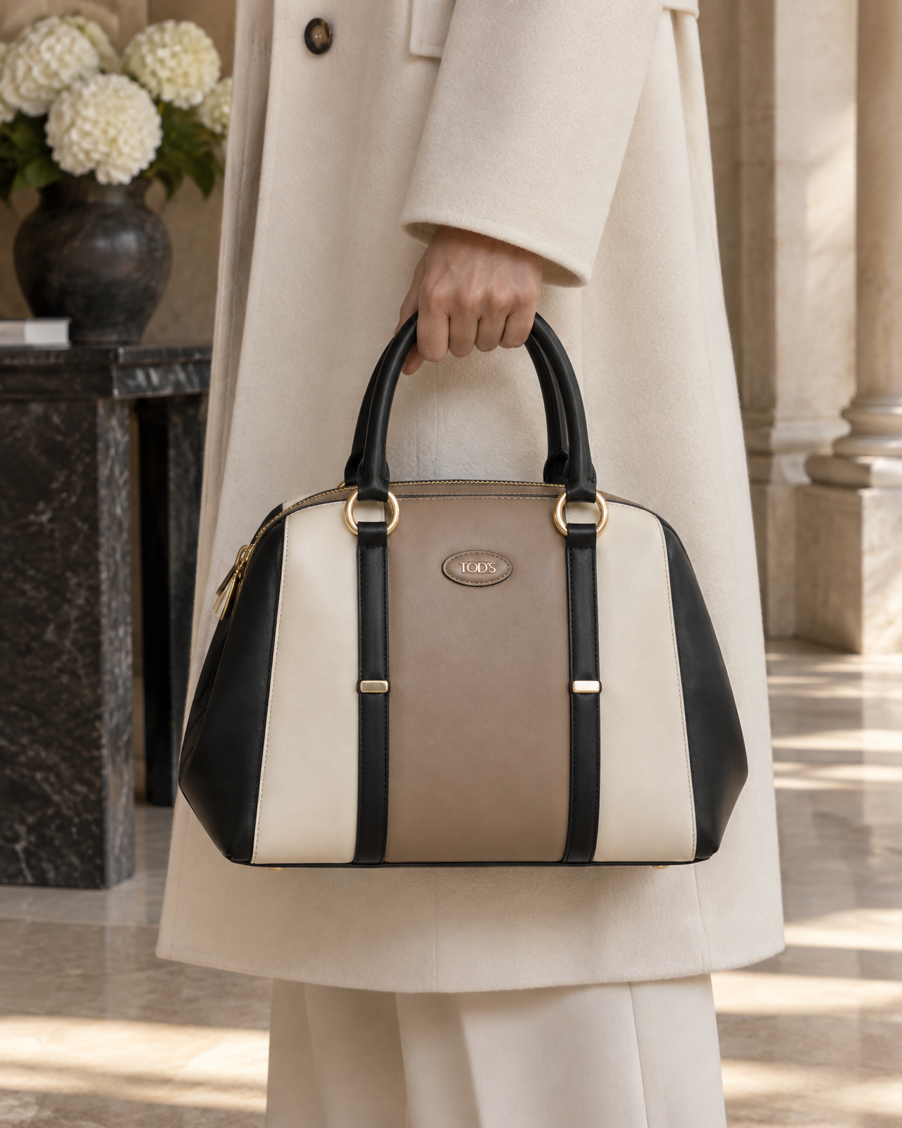 Model holding the black ivory and taupe Tod's top-handle bag