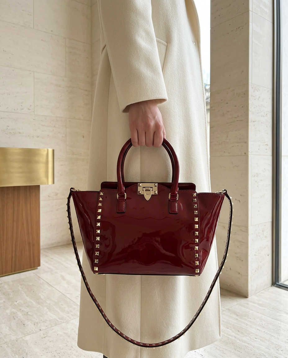 Model carrying the oxblood Valentino patent Rockstud tote